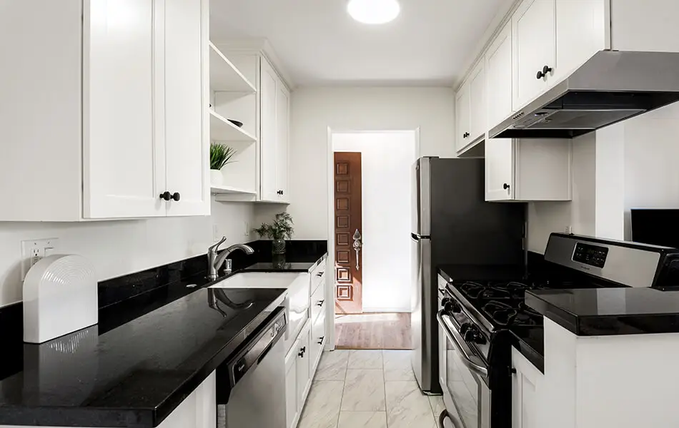 Galley kitchen with white cabinets black granite and stainless appliances at 11550 Nebraska Ave West Los Angeles condo